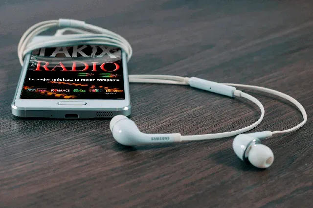 TAKIX Radio abierto en un teléfono junto a unos audífonos